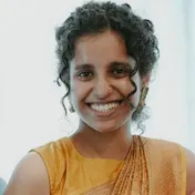 Vinitha Ajit smiling, with curly hair and a mustard top